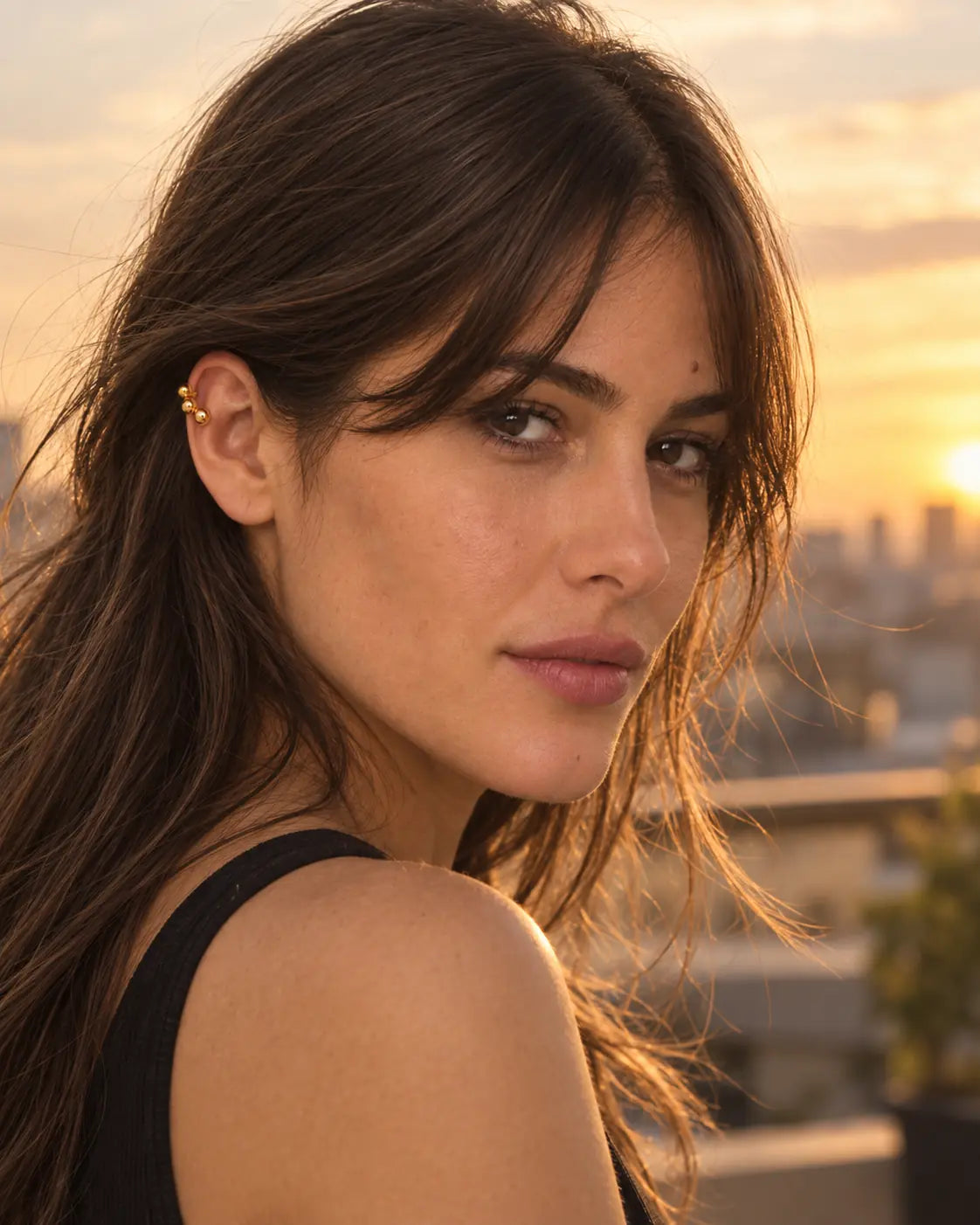 Woman wearing the Gold Orbit ear cuff outdoors at sunset. No piercing needed.