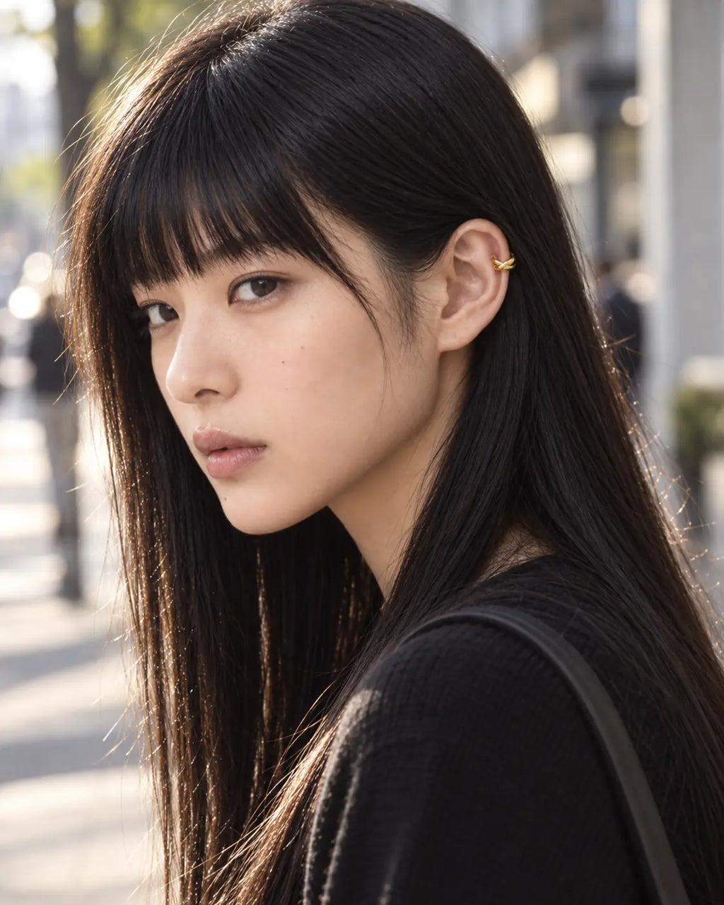 Woman wearing the gold Axis crossed ear cuff outdoors in an urban setting. No piercing needed.