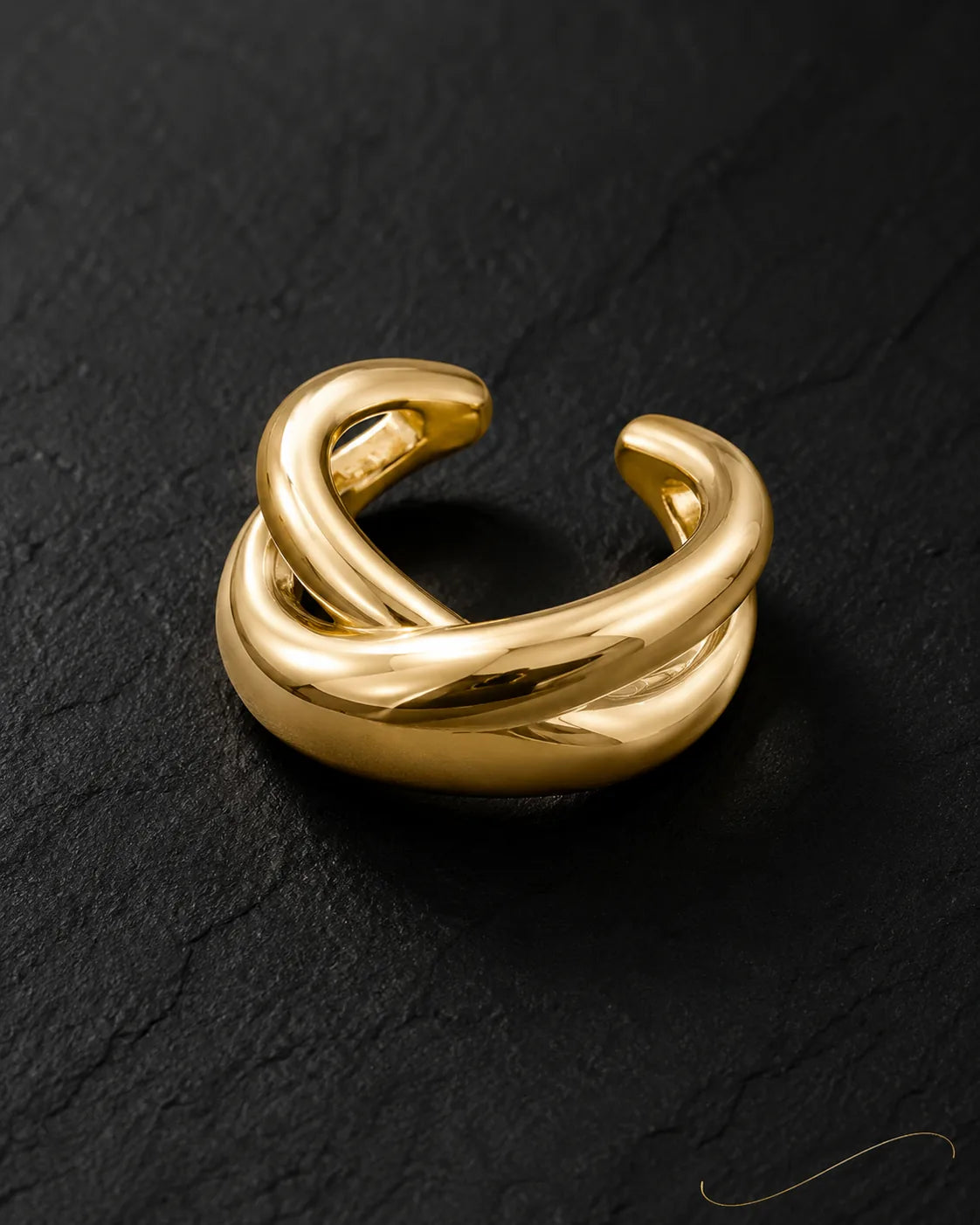 Single gold Axis ear cuff on dark stone, polished double-band crossing design, no piercing
