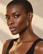 Jade baguette ear cuff with green channel-set stones on a woman's ear, warm background. No piercing needed.