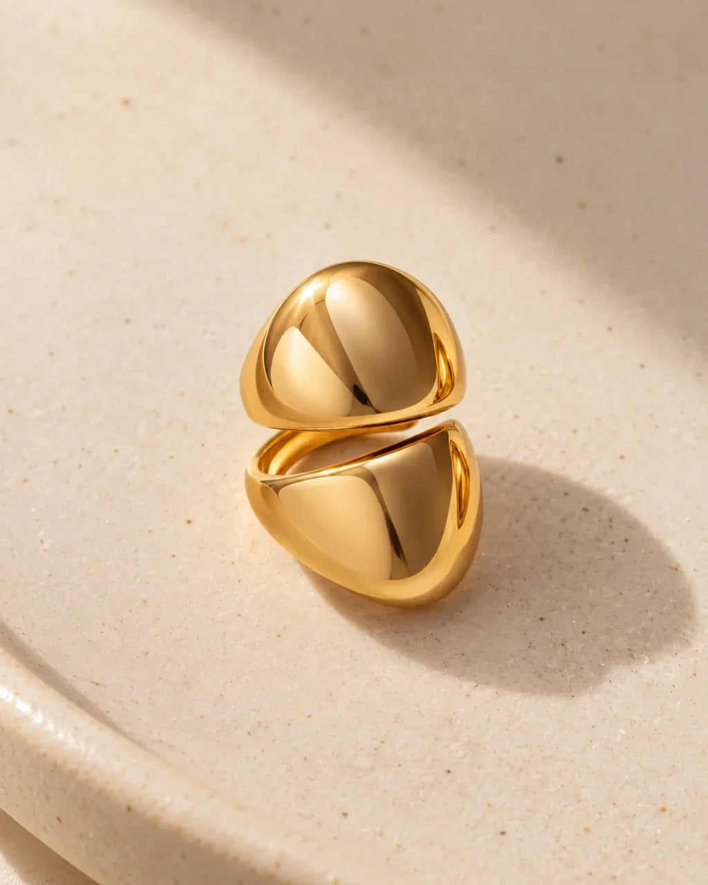 Echo Double Ear Cuff: two polished gold-tone domes on one cuff, resting on a pale ceramic dish.