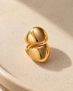 Echo Double Ear Cuff: two polished gold-tone domes on one cuff, resting on a pale ceramic dish.