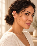 Woman with curly hair in a low bun wearing the gold Echo Double Ear Cuff on her upper ear, soft window light. No piercing needed.