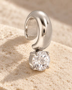 Silver Glint Drop Ear Cuff on pale stone, turned to show the open band that clips onto the ear. No piercing needed.