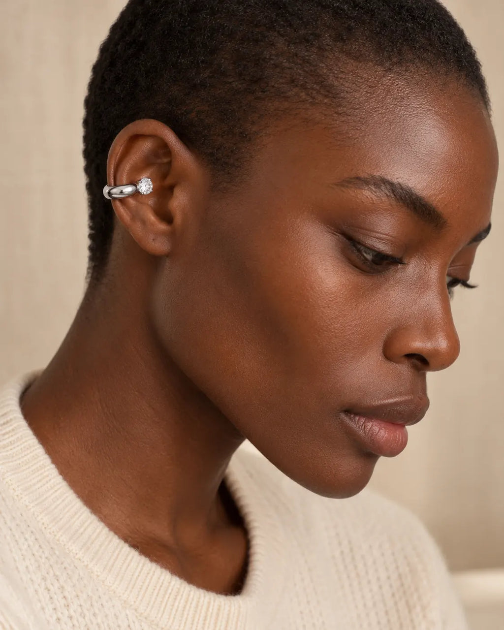 Silver drop ear cuff with one round stone on a woman's upper ear, side profile in soft window light. No piercing needed. Stainless steel.