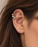 Silver Orbit ear cuff seen close on the upper ear, the graduated spheres following the curve of the cartilage. No piercing needed.