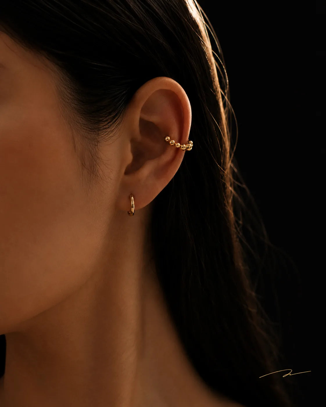 Gold Orbit ear cuff worn on the helix with a gold huggie on the lobe, no piercing needed