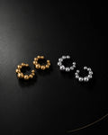 Orbit ear cuff in gold and silver pairs on black surface, graduated bead ear cuff no piercing