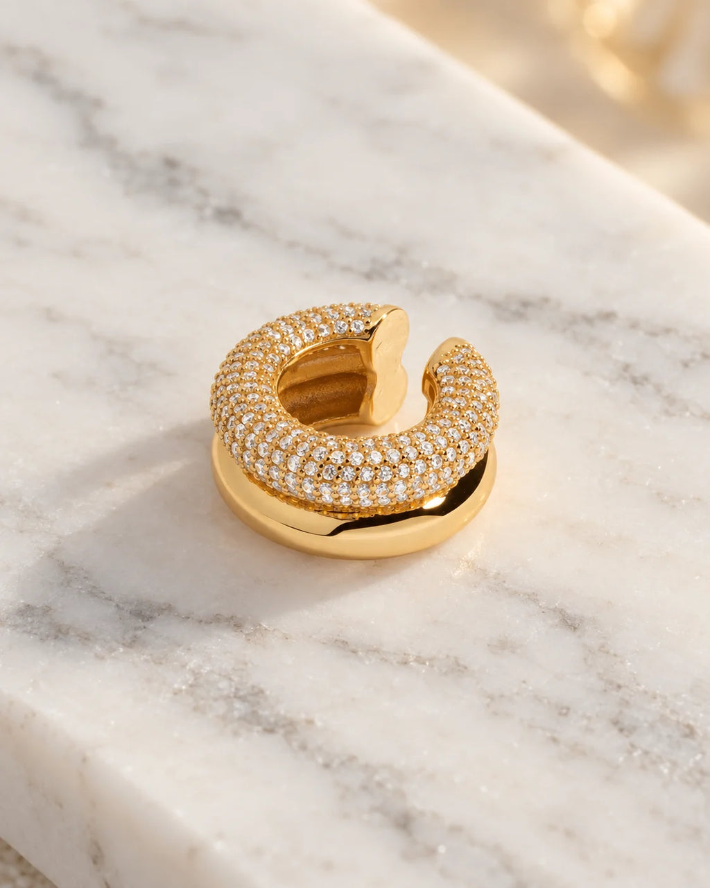 Close-up of the Gold Pave Dome ear cuff on white marble, showing the micro pave domed band against the polished lower band. Stainless steel.