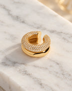 Close-up of the Gold Pave Dome ear cuff on white marble, showing the micro pave domed band against the polished lower band. Stainless steel.