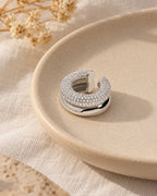 Close-up of the Silver Pave Dome ear cuff on a cream ceramic tray, micro zirconia paved across the domed band. Stainless steel.