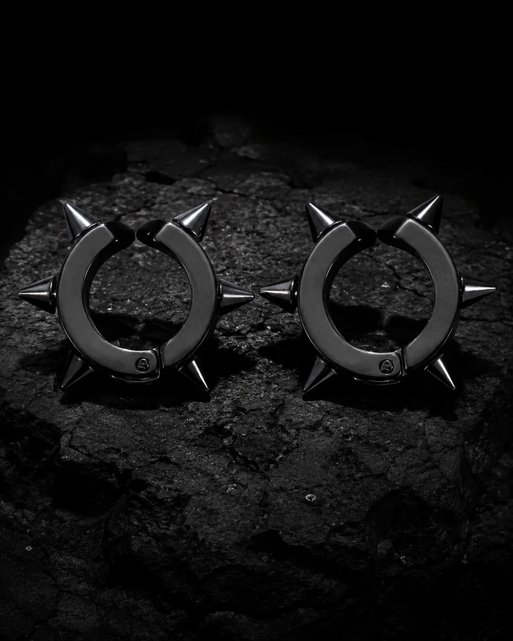 Pair of matte black spike ear cuffs on dark charcoal stone