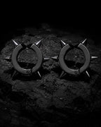 Pair of matte black spike ear cuffs on dark charcoal stone