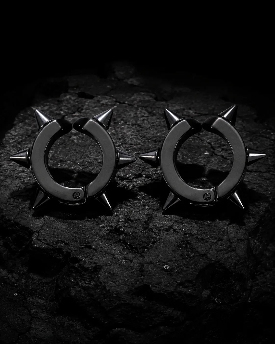 Pair of matte black spike ear cuffs on dark charcoal stone