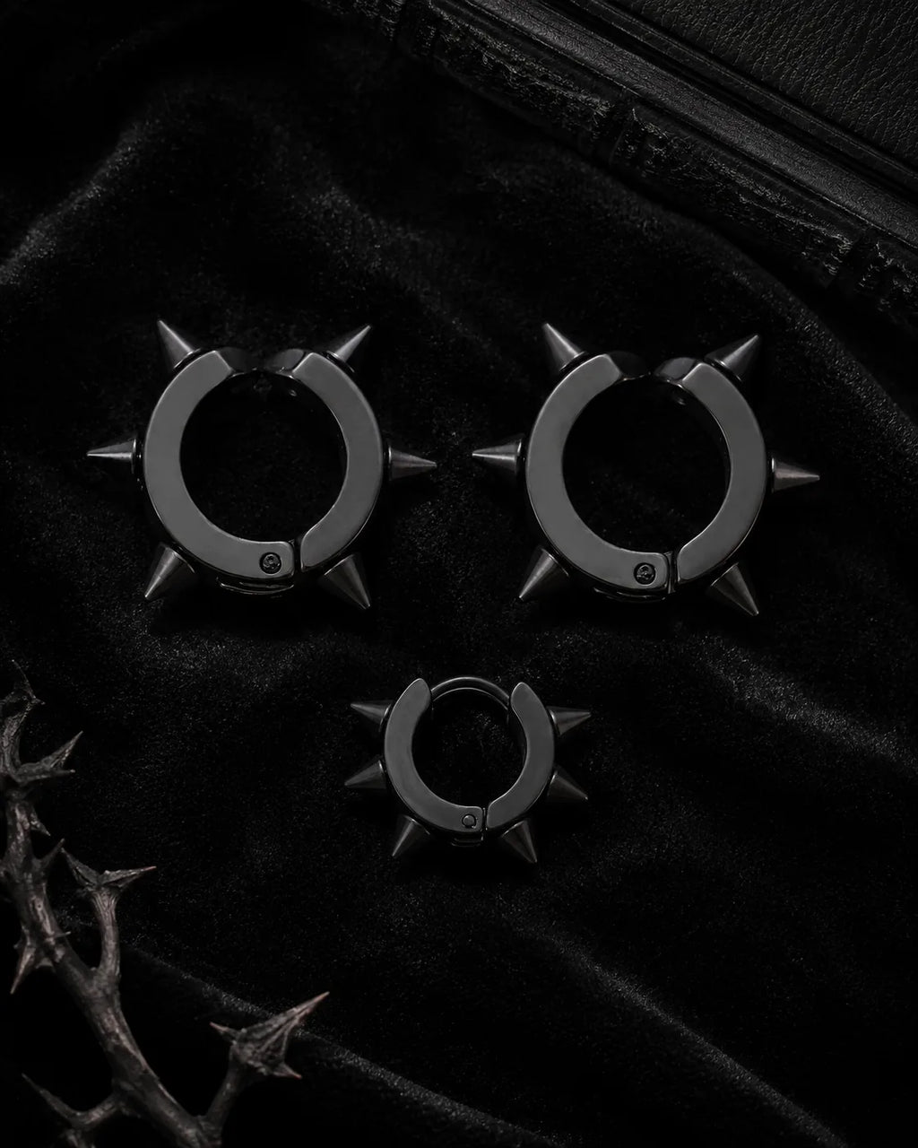 Matte black spike cuff set, three pieces, styled on black velvet with thorn branch