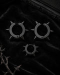 Matte black spike cuff set, three pieces, styled on black velvet with thorn branch