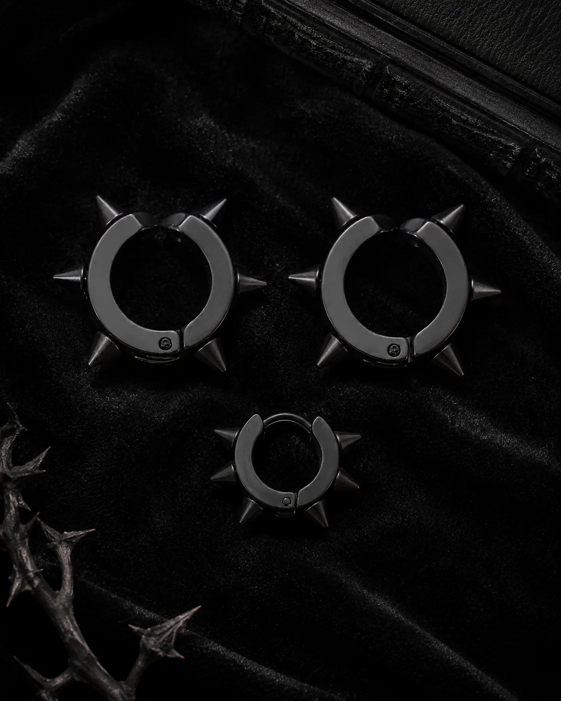 Matte black spike cuff set, three pieces, styled on black velvet with thorn branch