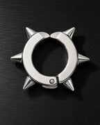 Silver spike ear cuff with sharp cone studs, close-up on dark brushed surface