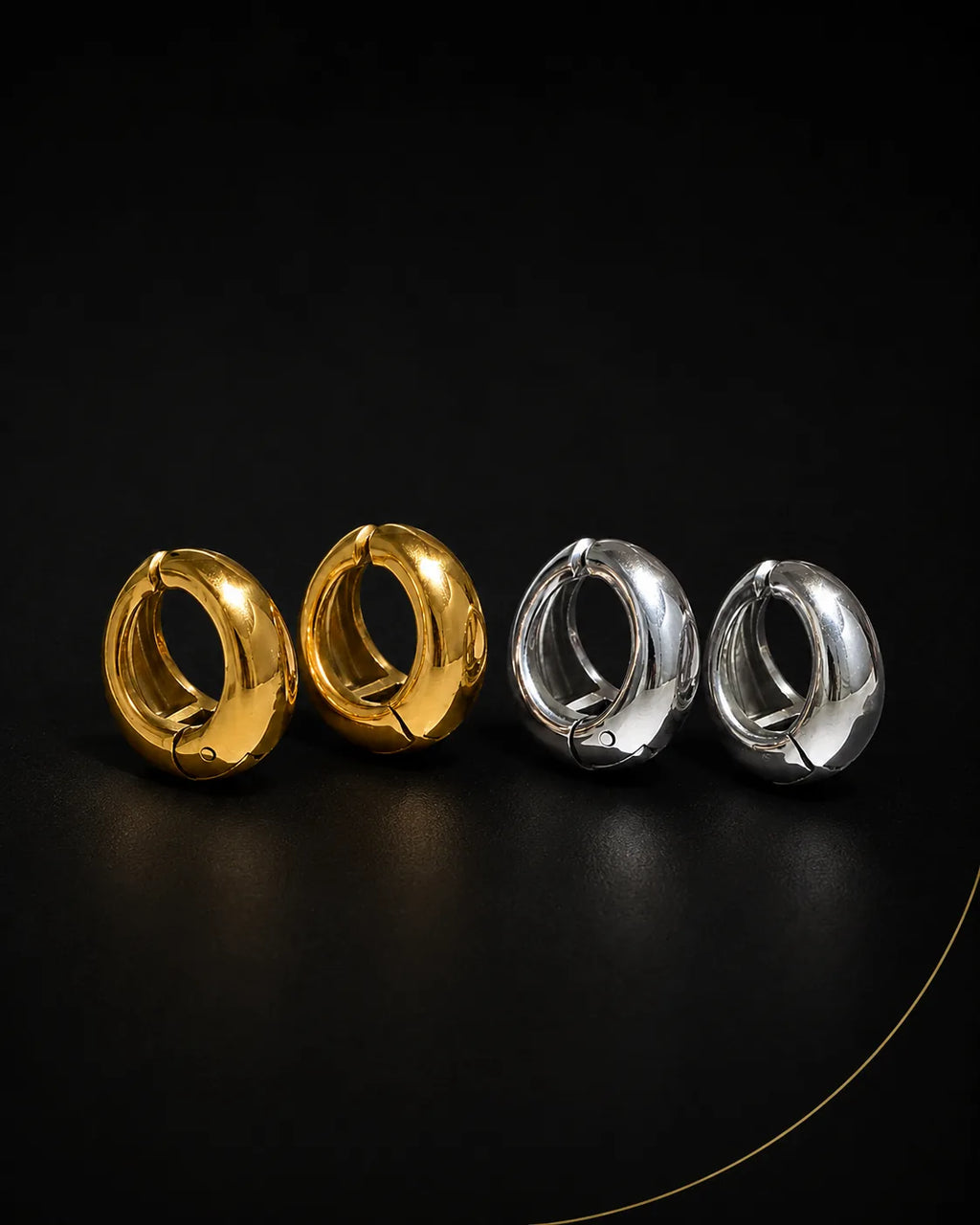 Vault Huggie in gold and silver pairs on black surface, chunky huggie earring no piercing needed