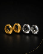 Vault Huggie in gold and silver pairs on black surface, chunky huggie earring no piercing needed