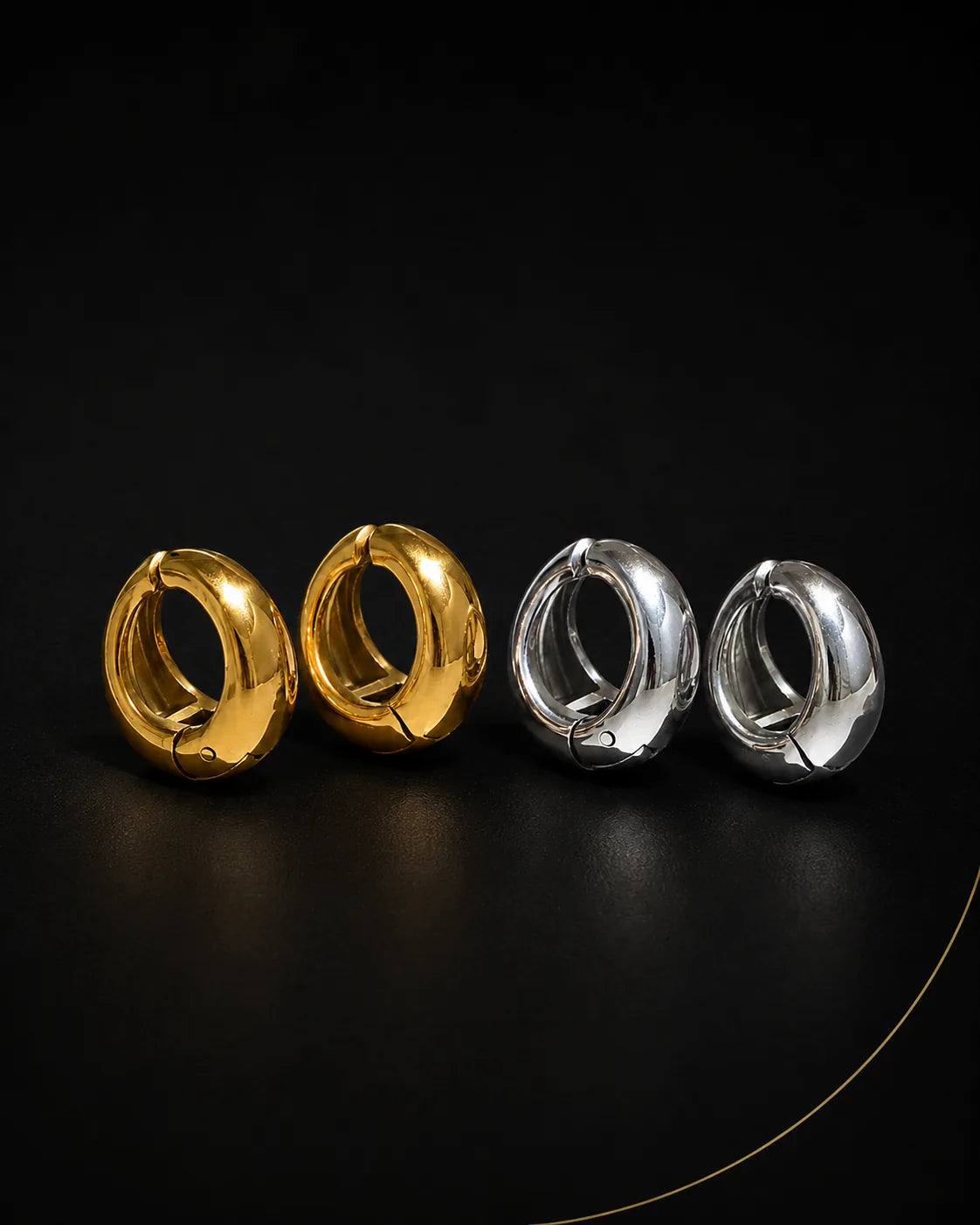 Vault Huggie in gold and silver pairs on black surface, chunky huggie earring no piercing needed