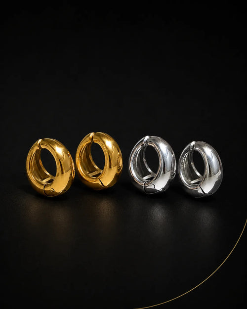 Vault Huggie in gold and silver pairs on black surface, chunky huggie earring no piercing needed