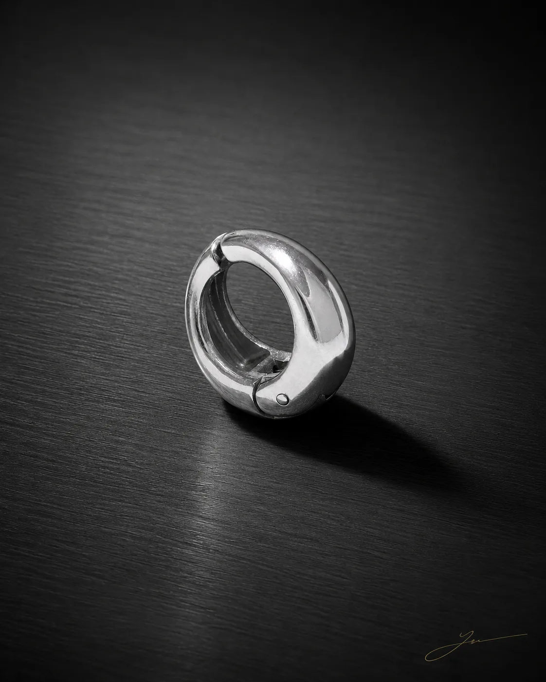 Single silver Vault Huggie on dark brushed surface, polished chunky huggie earring, no piercing